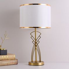 a lamp on a table next to some books and a bookend with a gold finish