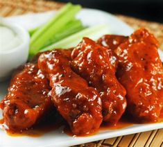 a plate topped with meat covered in sauce next to celery