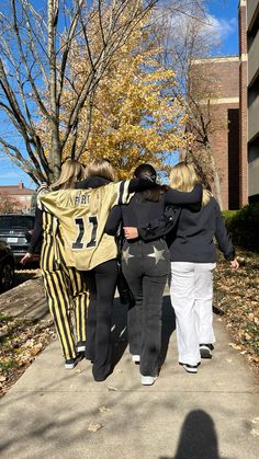 three women are walking down the sidewalk with their arms around each other and one is wearing a jersey