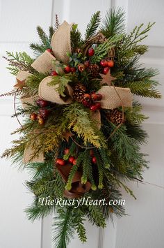 a wreath with pine cones, berries and burlocks hangs on the front door