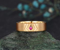 a gold ring with a pink diamond in the center on top of a green rock