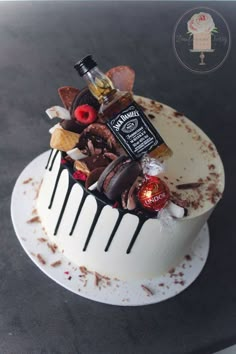 a white cake topped with lots of different types of candies and liquor bottles on top of it