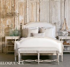 a white bed sitting next to a wooden wall