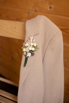 a boutonniere with flowers on the lapel of a jacket hanging from a wooden bench