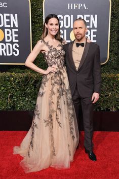 two people standing on a red carpet at an event