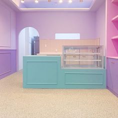 an empty counter in a room with pink and blue walls, white tile flooring and purple shelving