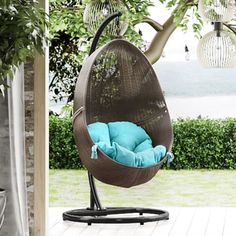 an outdoor swing chair with blue cushions on the back patio, next to a potted tree