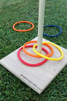 a wooden board with rings on it and a stick sticking out of the middle in the grass