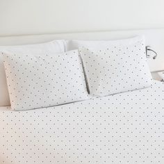 a bed with white sheets and polka dot pillows