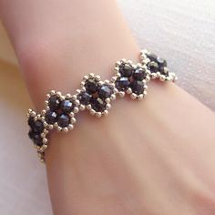 About this item-- Elevate your style with this delicate four-leaf clover bracelet, crafted with exquisite iridescent black crystals and silver seed beads. It features a matching silver-colored toggle clasp for a secure and stylish closure, all woven together with super-strong, micro-fused braided thread. Perfect for any occasion, this bracelet is a must-have addition to your jewelry collection! One-of-a-kind piece available in only one size. Please take a moment to check the measurements to ensure a perfect fit. Specs-- Measurement: Length - 190 mm (7.5 inches) Width - 17 mm (0.66 inches) Material: crystal, Japanese galvanized silver (plated) bead, micro-fused braided thread Color: iridescent black, silver Hardware: toggle clasp Weight: 16 grams Production ID: BR043 Elegant Beaded Flower Crystal Bracelet, Elegant Flower-shaped Beaded Crystal Bracelet, Elegant Handmade Flower Beaded Bracelets, Elegant Beaded Bracelets With Flower-shaped Spacer Beads, Seed Beads Bracelet, Iridescent Black, Clover Bracelet, Diy Bracelet Designs, Seed Bead Bracelets