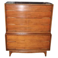 a wooden dresser with black marble top on it's sides and bottom drawer open