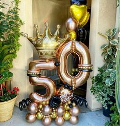 the number 50 is made out of balloons in front of some plants and potted plants