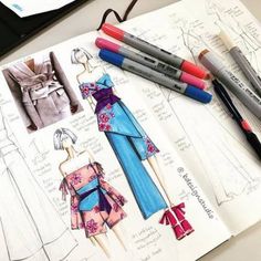 paper dolls and crayon markers on top of a drawing book with fashion sketches