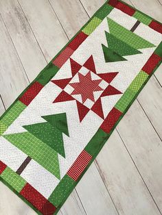 a green and red table runner with christmas trees on the top, sitting on a wooden floor