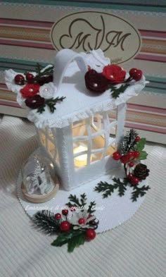 a small white candle holder with holly and red berries on it next to a christmas card