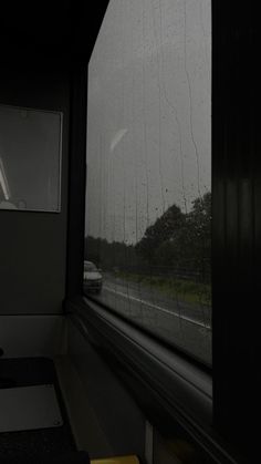 the rain is coming down on an empty train car as seen from inside a window