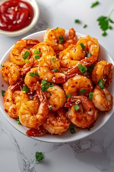 a white bowl filled with cooked shrimp and garnished with cilantro sauce