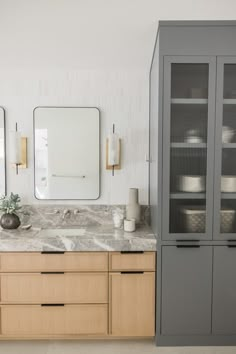 a bathroom with marble counter tops and wooden cabinets in the corner, along with two large mirrors on the wall