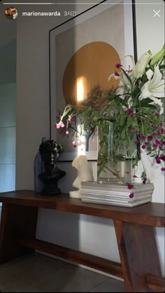 a vase with flowers sitting on top of a wooden table in front of a mirror