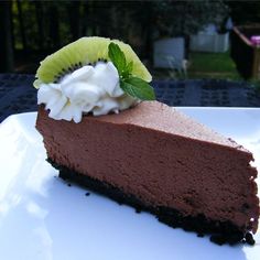 a piece of chocolate cheesecake with whipped cream and a kiwi slice on top