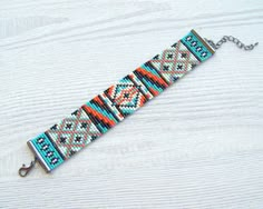 a beaded bracelet is shown on a white surface with a metal hook in the middle