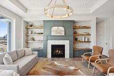 a living room filled with furniture and a fire place under a chandelier in front of a window