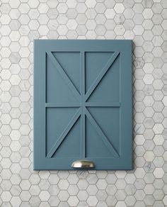 a blue square shaped object mounted on a wall with hexagonal tiles in the background