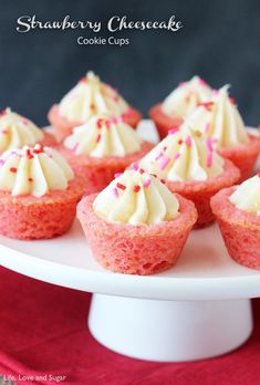 strawberry cheesecake cupcakes on a white cake plate with sprinkles