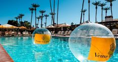 two inflatable balls floating on top of a swimming pool next to palm trees