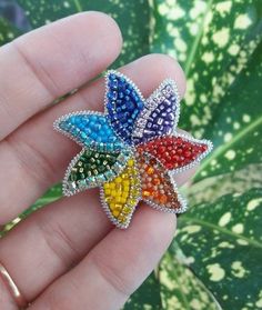 a person holding a colorful brooch in their hand