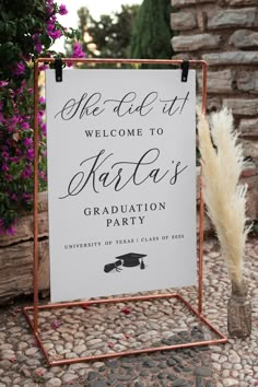 a welcome sign for a graduation party is displayed on a stand with flowers in the background