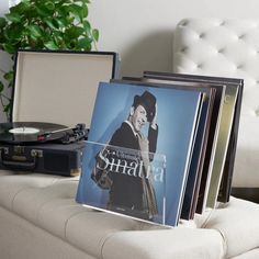 a record player sitting on top of a white couch next to a stack of records