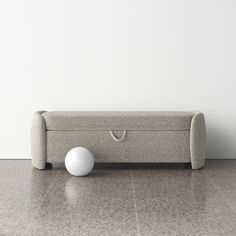 a white ball sitting on the floor next to a gray bench with two holes in it