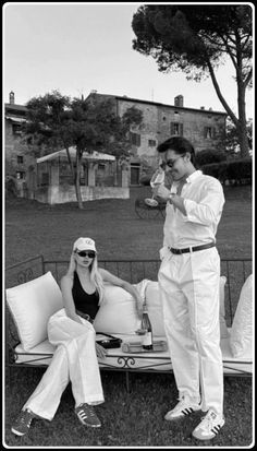 a man standing next to a woman sitting on top of a bed in the grass