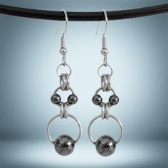 two silver balls hanging from hooks on a black wire with a blue back ground behind them