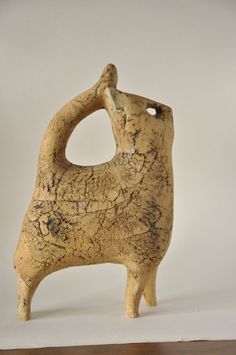 a ceramic sculpture of a dog on a wooden table with a white wall in the background