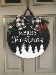 a merry christmas sign hanging on the front door with pine trees and plaid bow tie