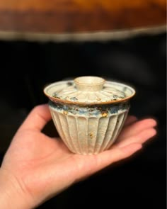 a hand is holding a small white cup