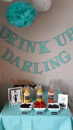 a blue table topped with fruit and drinks next to a sign that says drink up dardling