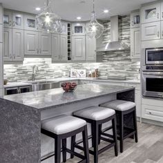 a kitchen with marble counter tops and stools next to an island in the middle