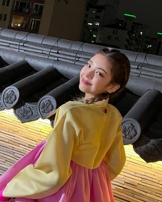 a woman in a yellow and pink dress standing next to a row of black umbrellas