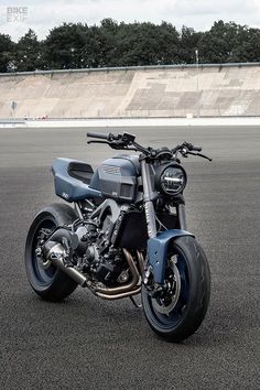 a blue motorcycle parked on top of a parking lot next to a large concrete wall