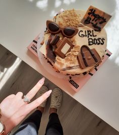 a woman's hand is pointing at a cake with chocolate decorations on it that says girl boss