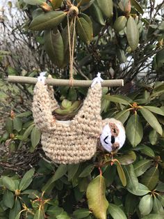 a crocheted baby bib hanging from a tree branch with a stuffed animal