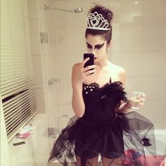 a woman in a black dress is looking at her cell phone while wearing a tiara