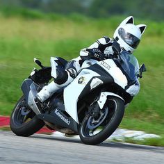 a person riding a motorcycle on a track with grass and trees in the back ground