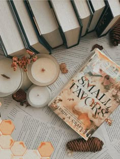 some candles and books on top of a table with pine cones, leaves and honeycombs