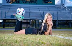 a woman laying on the ground with a soccer ball in her hand and smiling at the camera