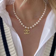 a woman wearing a pearl necklace with a gold pendant