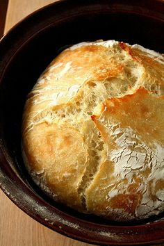 a loaf of bread sitting in a bowl on top of a wooden table